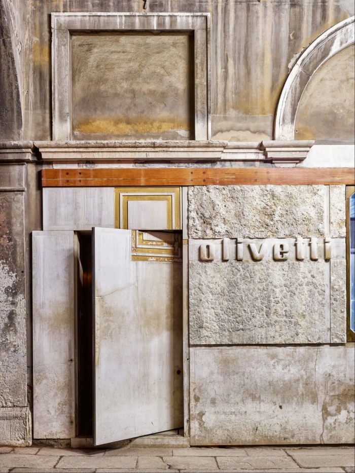 A half-open secret stone door at the front of the Olivetti shwroom