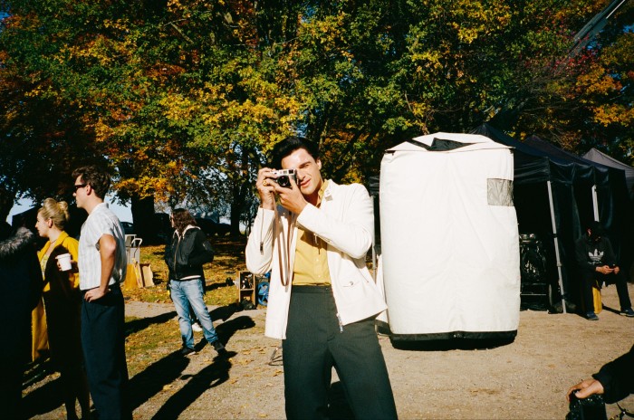 Jacob Elordi taking photographs on the set of Priscilla