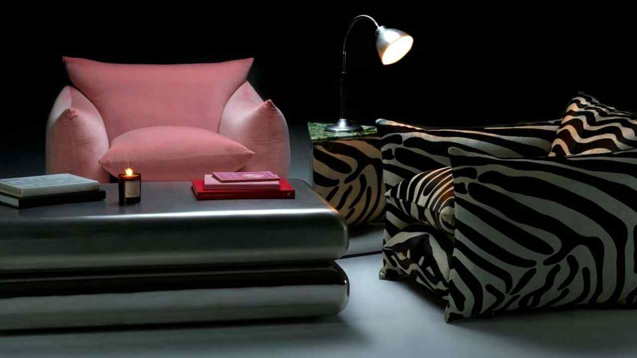 Velvet pink armchair and zebra-print chair with a steel coffee table, books, candle, and desk lamp