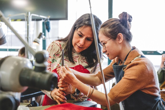 Two women working together on a metalworking project in a workshop